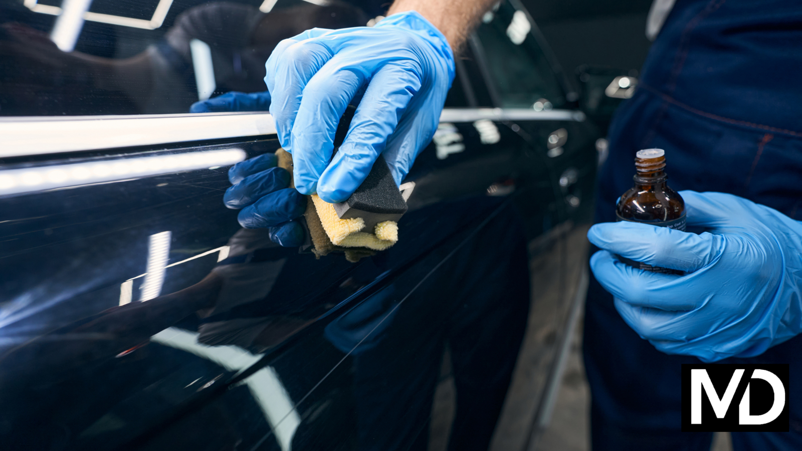 a person wearing gloves and holding a sponge over a car